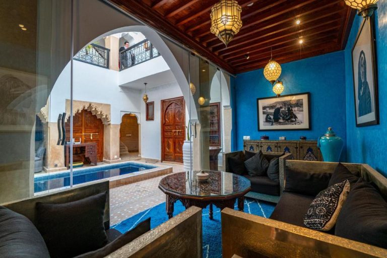 Salón con paredes azules y patio interior con piscina del Riad Serendip en Marrakech