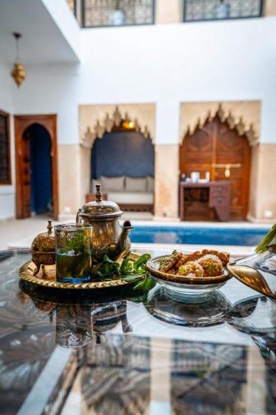 Servicio de té marroquí con dulces típicos en el patio interior con piscina del Riad Serendip