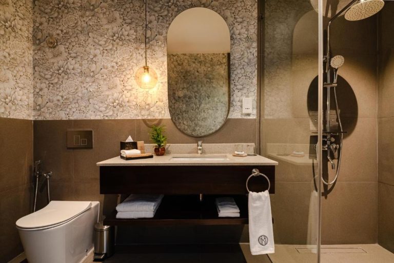 Baño moderno con ducha, lavabo y papel pintado floral del hotel MK Colombo en Colombo