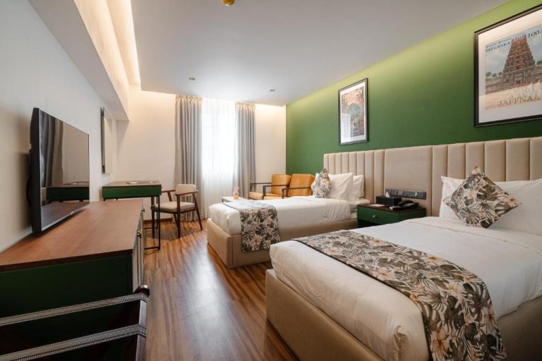 Habitación doble twin con paredes verdes y decoración tropical en el hotel MK Colombo, Sri Lanka