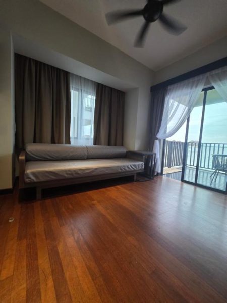 Salón con sofá y suelos de madera con vistas al mar desde balcón en Golden Palm Tree Suite Sepang