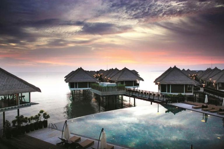 Villas sobre el agua al atardecer con piscina infinity en Golden Palm Tree Suite Sepang, Malasia