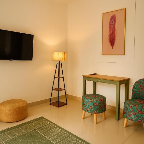 Sala de estar con escritorio verde, sillón floral y televisión en Hotel Amore Mio Morjim