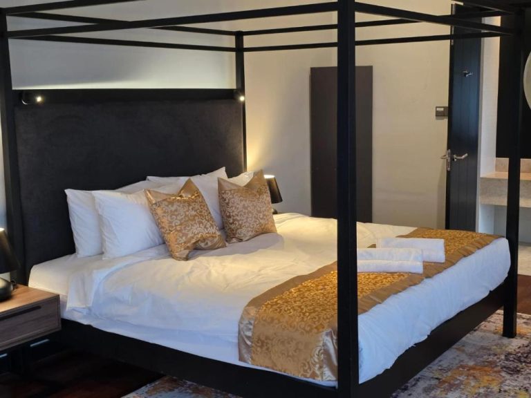 Habitación de lujo con cama de dosel negra y detalles dorados en Golden Palm Tree Suite Sepang Malasia