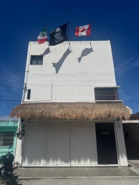 Fachada exterior del La Perle Noire Dive Hotel Cozumel con banderas de México y Canadá en azotea