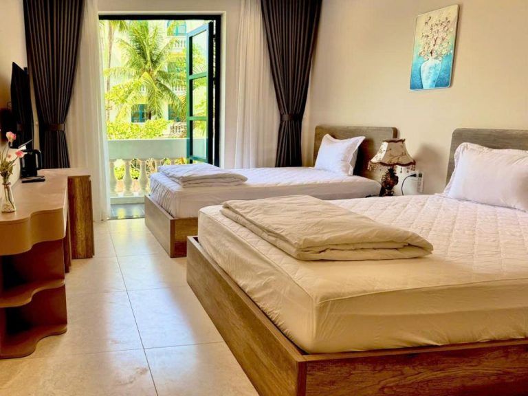 Habitación triple con dos camas y balcón con vistas a palmeras en Minh Anh Hotel