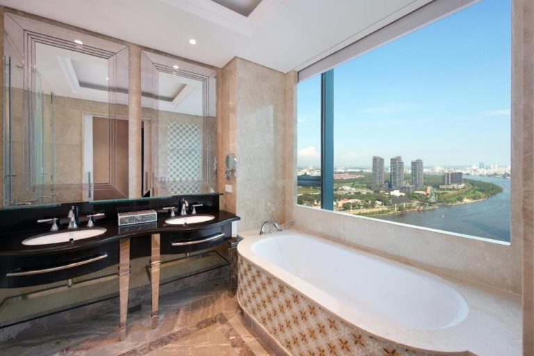 Lujoso baño con bañera y vistas panorámicas al río en The Reverie Saigon Residential Suites