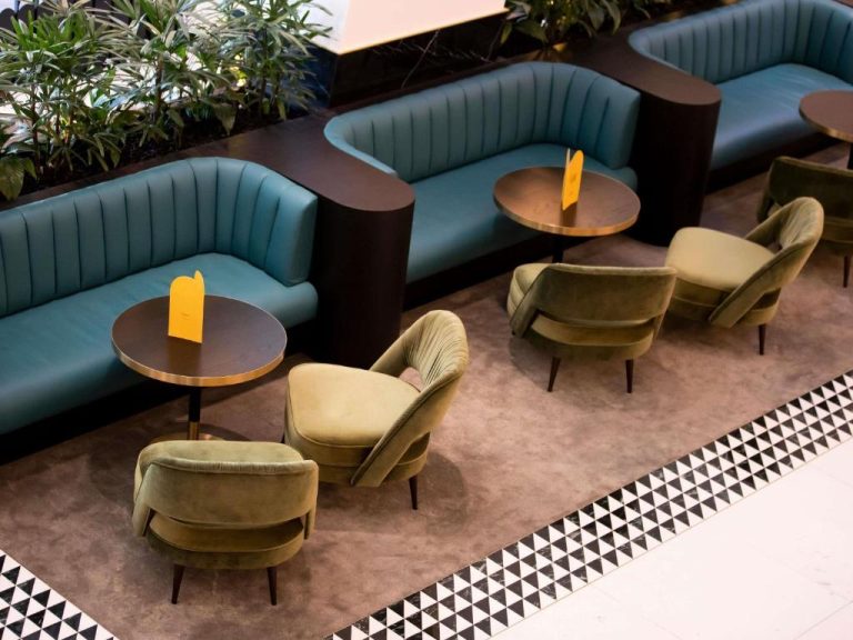 Elegante lobby lounge del Swissotel Sydney con sofás turquesa y sillones verdes de terciopelo