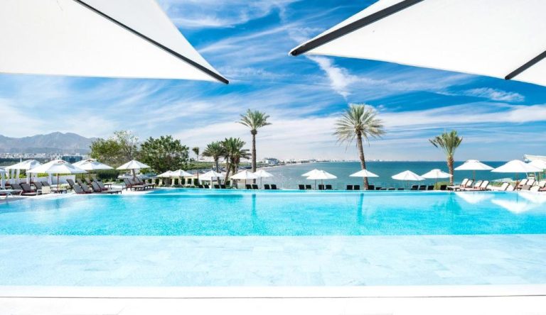 Piscina infinita con vistas al mar y tumbonas del Crowne Plaza Muscat by IHG en Omán