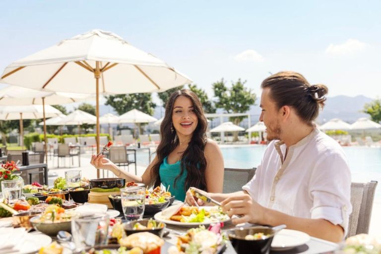 Pareja disfrutando de un almuerzo en la terraza del restaurante junto a la piscina del Crowne Plaza Muscat