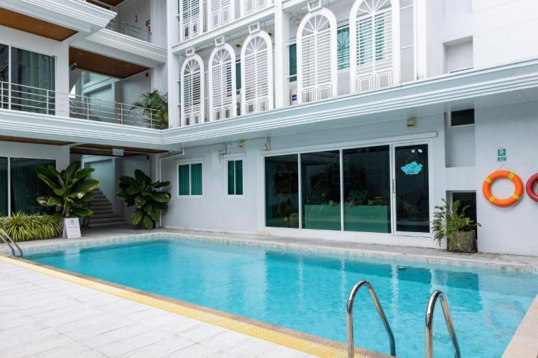 Piscina exterior del Peranakan House con fachada colonial blanca y zonas ajardinadas