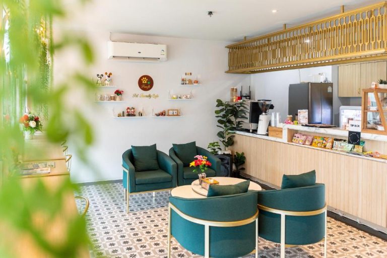 Zona de café interior con sillones verdes y mostrador en Peranakan House, ambiente acogedor pet friendly
