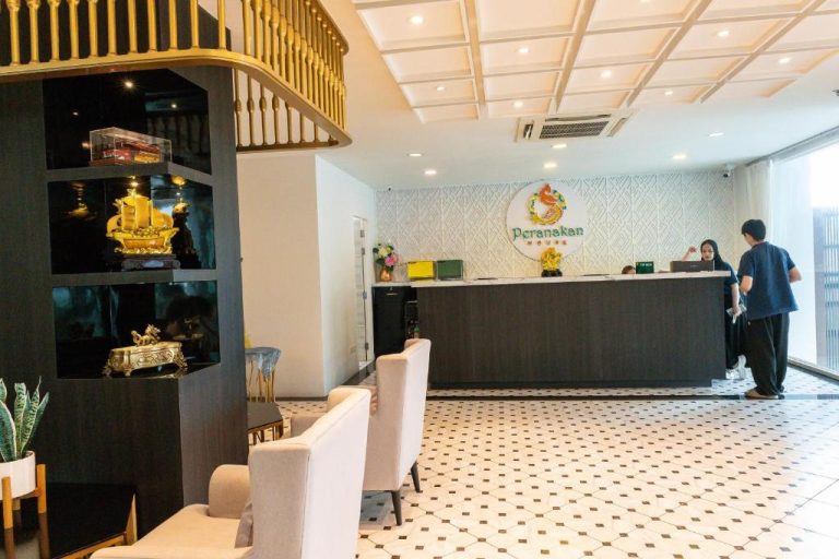 Recepción y lobby del Peranakan House con decoración dorada y suelo de mosaico blanco
