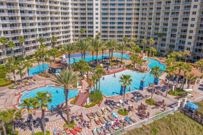 Complejo de piscinas exteriores con palmeras y tumbonas en Shores of Panama, Panama City Beach