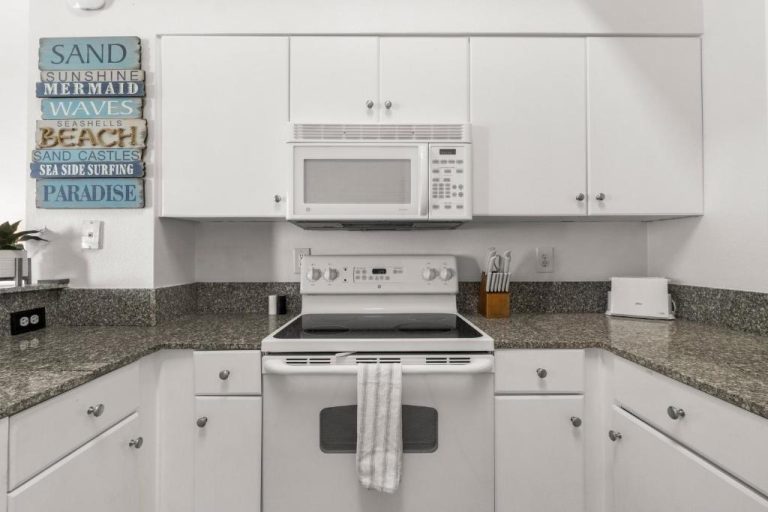 Cocina totalmente equipada con electrodomésticos blancos y encimera de granito en Shores of Panama 108