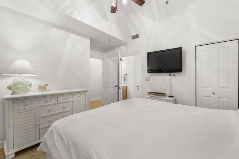 Habitación principal blanca con cama doble, televisor en pared y vestidor en Shores of Panama Unit 108