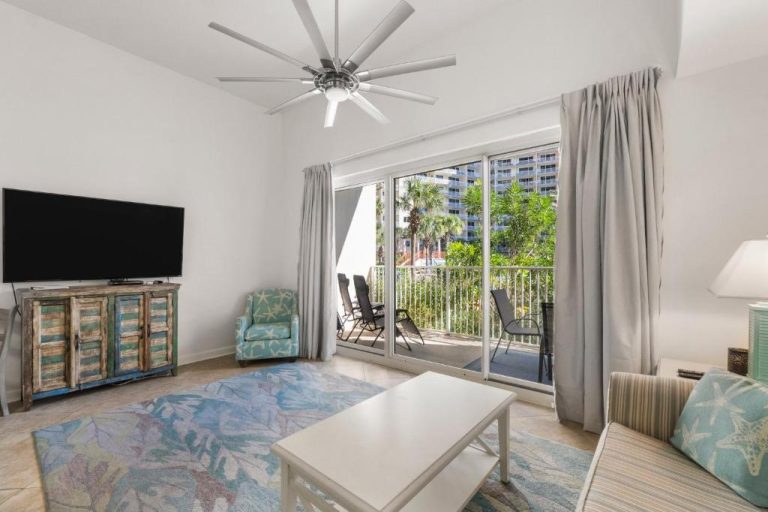 Sala de estar con televisor, mueble rústico y balcón con vistas en Shores of Panama Unit 108