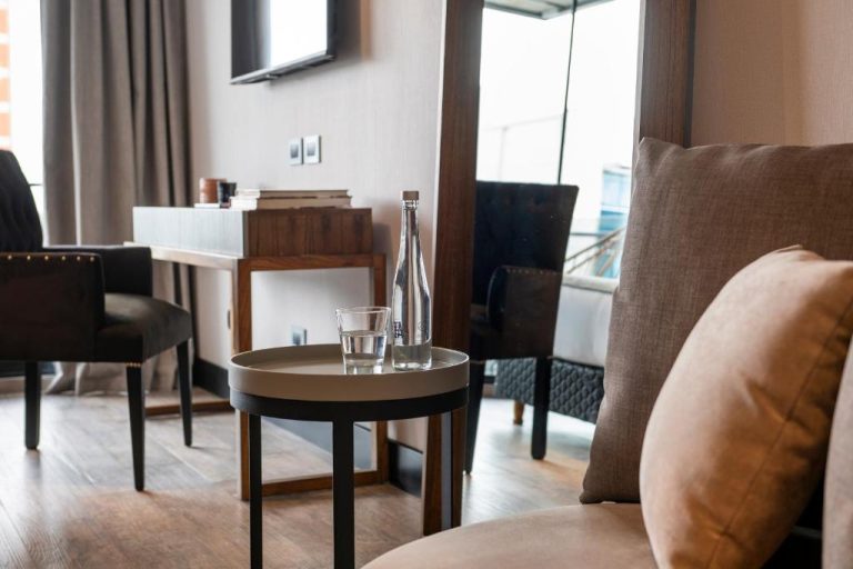 Salón elegante con mesa auxiliar, botella de agua y sofá en Casa Joseph Libertador