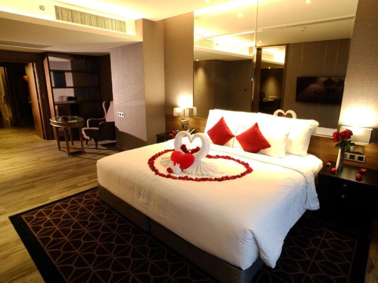 Habitación romántica del Ayathorn Bangkok con cama decorada con pétalos de rosa y figuras de cisnes