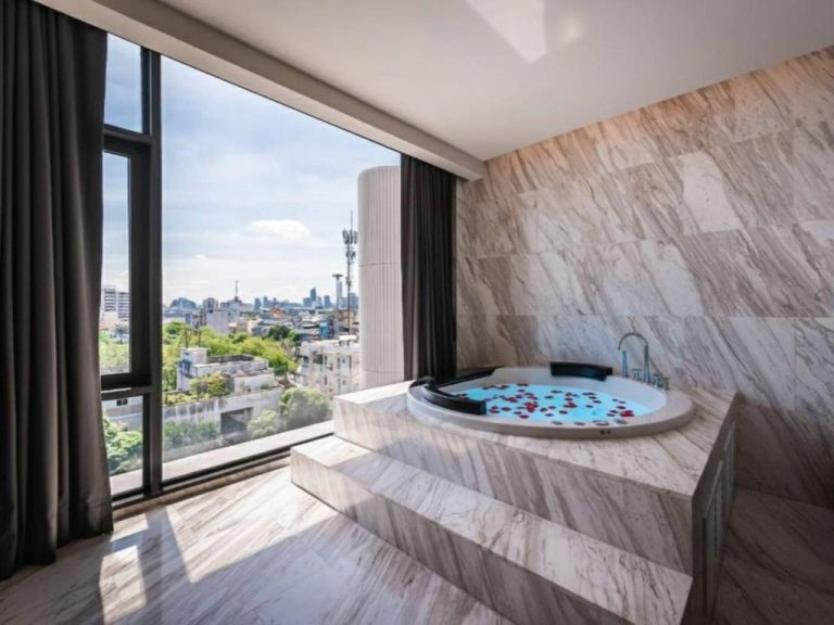 Jacuzzi redondo con pétalos de rosa y vistas panorámicas a la ciudad en el Ayathorn Bangkok