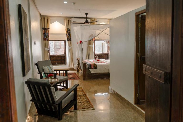 Habitación con cama de dosel y zona de estar en Emerald Palm Courtyard Hotel