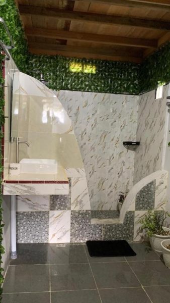 Baño exterior con azulejos de mármol, lavabo moderno y ducha al aire libre en Ricky's Beach House
