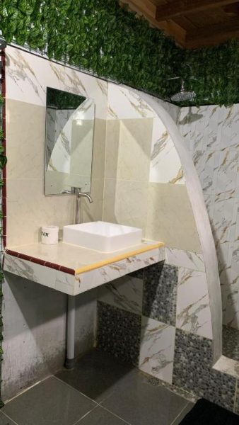 Baño moderno con lavabo sobre encimera de mármol y ducha de lluvia en Ricky's Beach House