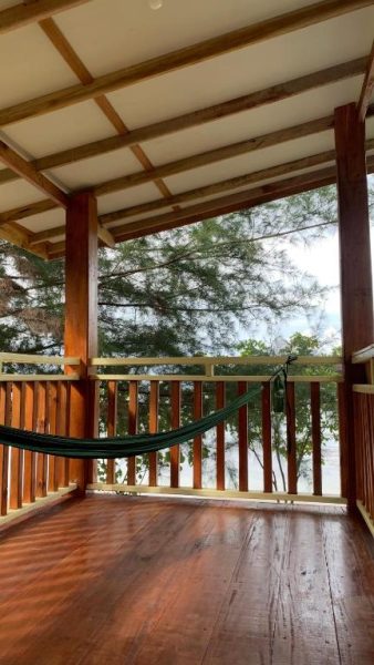 Terraza de madera con hamaca y vistas al mar en Ricky's Beach House