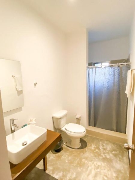 Baño completo con ducha y cortina en Balam Suites, con lavabo moderno y acabados contemporáneos