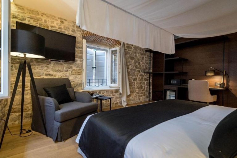 Habitación doble con cama king, pared de piedra y TV en Murum Heritage Hotel