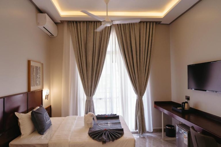 Habitación doble de lujo con cama, TV y ventilador de techo en Elephanto Hotel LTD