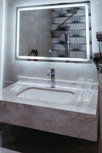 Baño moderno con lavabo de mármol y espejo retroiluminado LED en Elephanto Hotel LTD