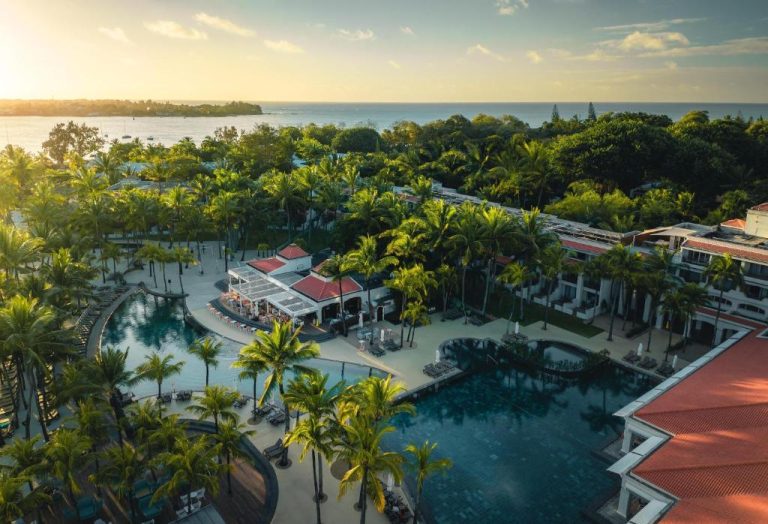 Vista aérea de las piscinas exteriores rodeadas de palmeras del Mauricia Beachcomber Resort & Spa