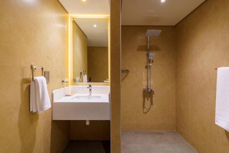 Baño moderno con ducha de lluvia y lavabo en el Jarzez Inn Hotel Azaiba