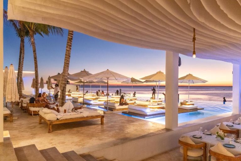 Piscina infinita con tumbonas blancas y vistas al mar al atardecer en Le Saint Tropez