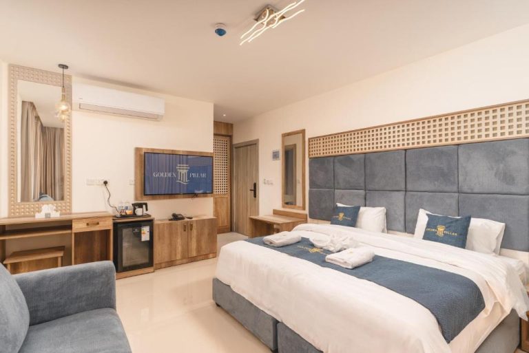 Habitación doble deluxe con cama king size y cabecero azul en el Golden Pillar Hotel