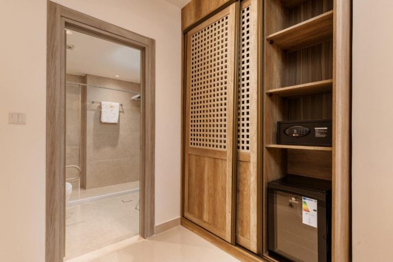 Armario de madera con celosía, caja fuerte y minibar del Golden Pillar Hotel junto al baño privado