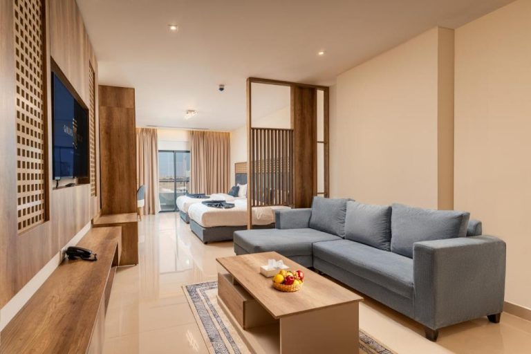 Suite con salón y sofá gris, televisión y dormitorio separado en Golden Pillar Hotel