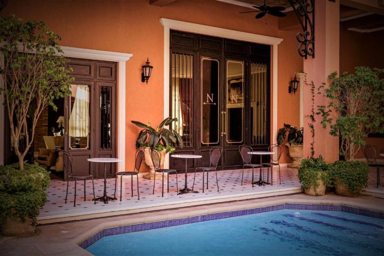 Terraza con mesas y sillas junto a la piscina exterior del Nino Hotel Boutique