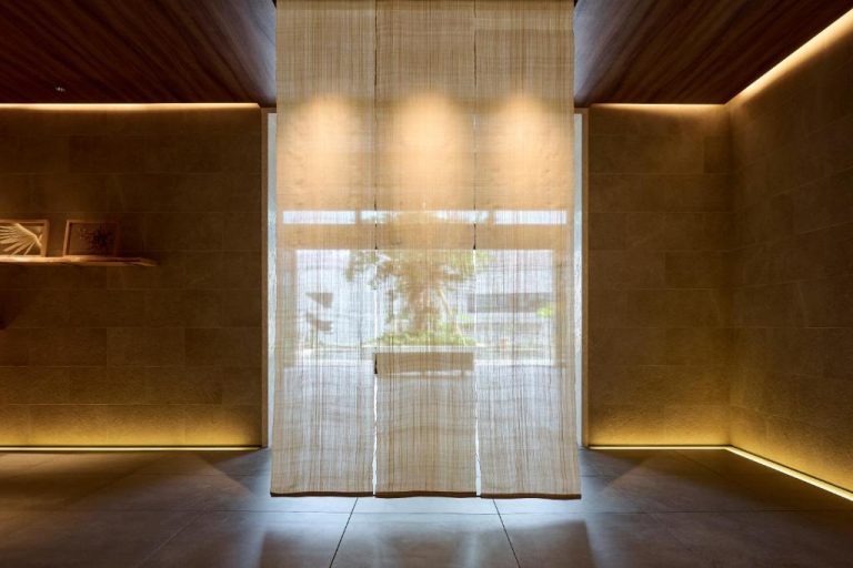 Elegante lobby del Royal Park Hotel Iconic Naha con cortinas traslúcidas e iluminación cálida ambiental
