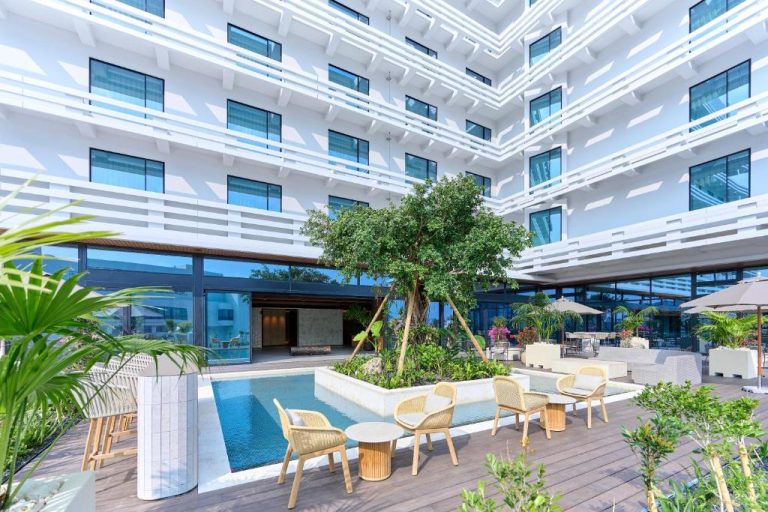Terraza exterior con piscina, jardín tropical y zona lounge del Royal Park Hotel Iconic Naha