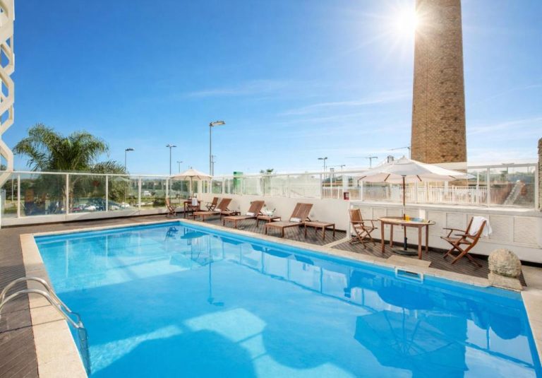 Piscina exterior con tumbonas y sombrillas en la terraza del Hotel Intercity Florianópolis