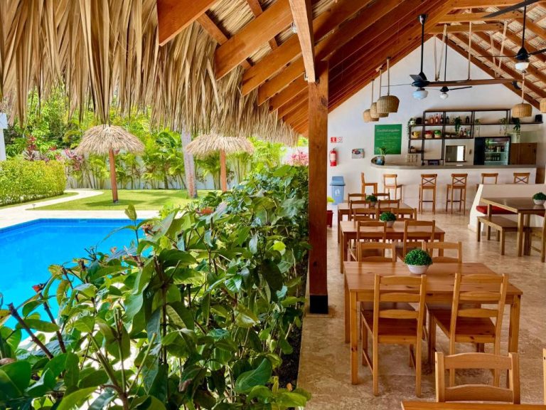 Restaurante con techo de palma y vistas a la piscina exterior en La Curadiña Encuentro Surf Hotel