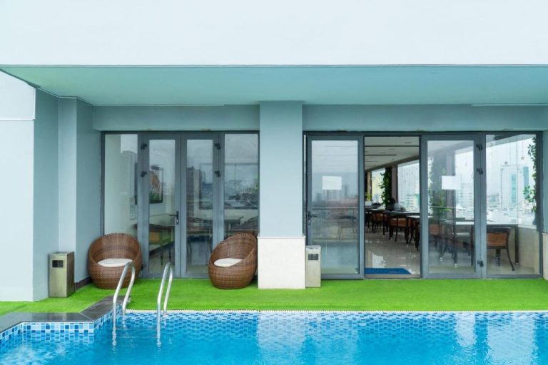 Piscina exterior con terraza y sillas de ratán en Quoc Cuong Hotel & Apartment Danang by Haviland