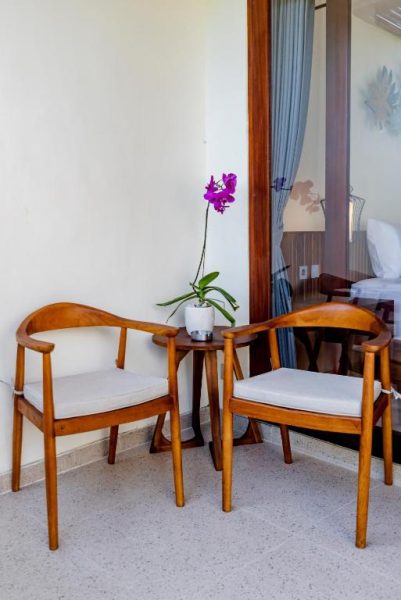Terraza con dos sillas de madera y orquídea en maceta del Svadarma Bali Villa by Dhananjaya Hospitality