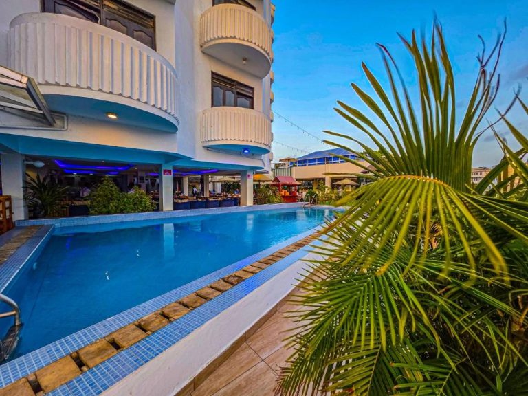 Piscina exterior con terraza y palmeras del Hotel Sapphire junto al restaurante con iluminación azul