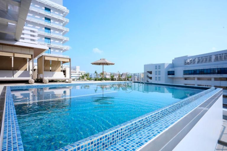 Piscina exterior en terraza del The Royal Park Hotel Iconic Naha con tumbonas y vistas al cielo azul