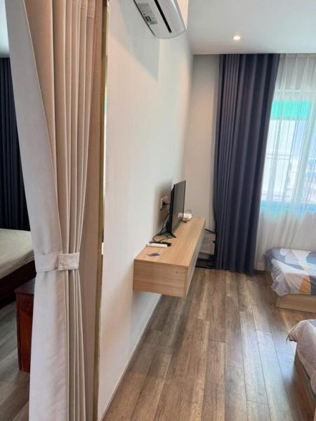 Habitación moderna con televisor en repisa flotante y suelo de madera en Green Inn Phu Quoc Hotel