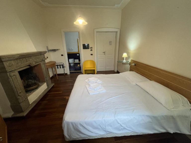 Habitación doble con chimenea de piedra y cama matrimonial en el Hotel Liberty