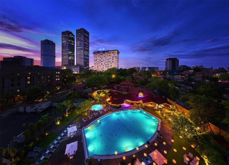 Vista aérea nocturna de la piscina exterior iluminada del Hilton Colombo con skyline de la ciudad